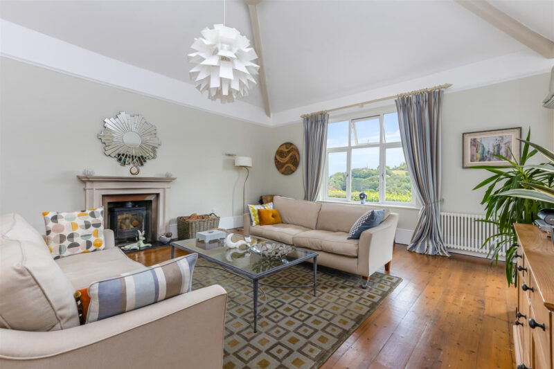 Elegant sitting room with high ceilings, exposed oak flooring and feature log burner.
